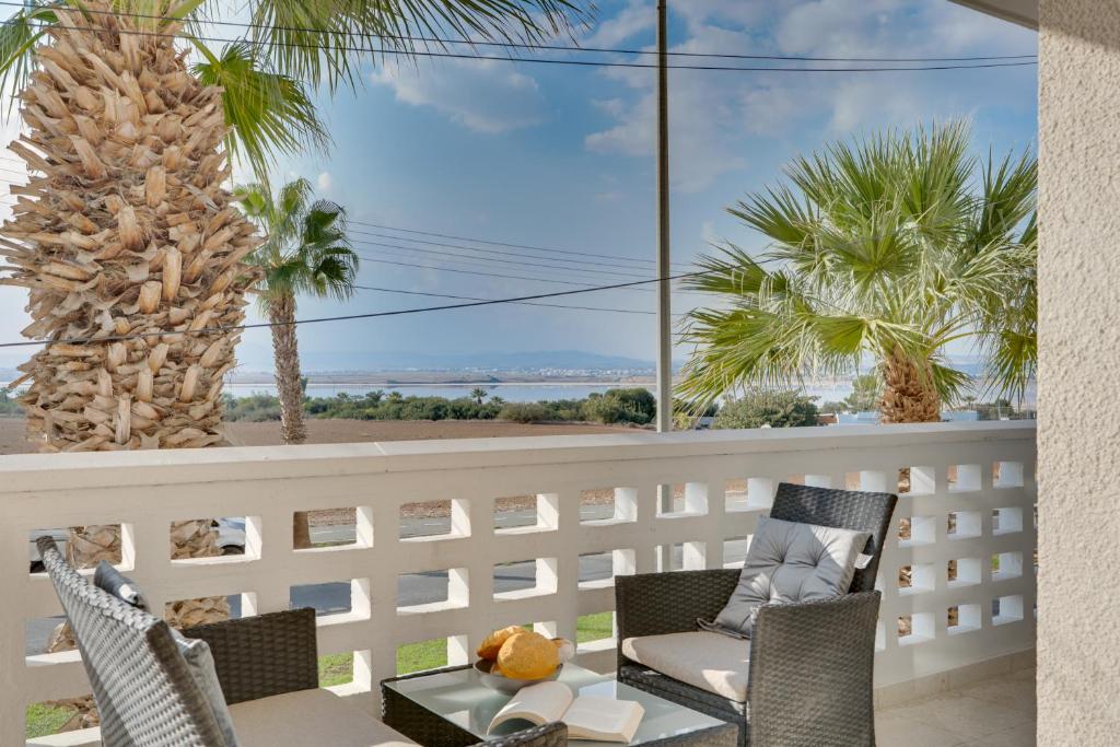 einen Balkon mit einem Tisch, Stühlen und Palmen in der Unterkunft Elisabeth Salt Lake views 200m from Makenzy beach in Larnaka