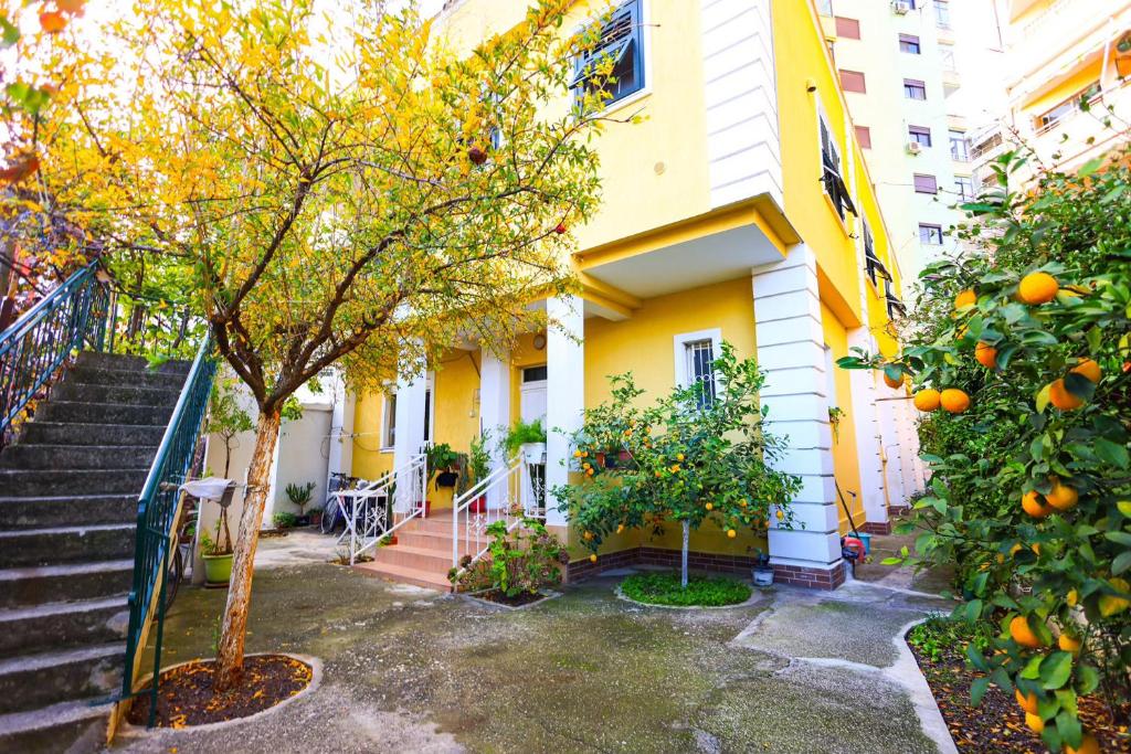 an orange tree in front of a yellow building at Apartment with garden in the center of Durres in Durrës