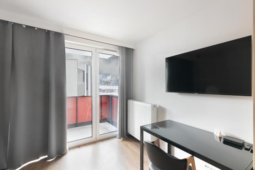 Habitación con escritorio, TV y ventana. en Apartamenty Platinex 1, en Cracovia