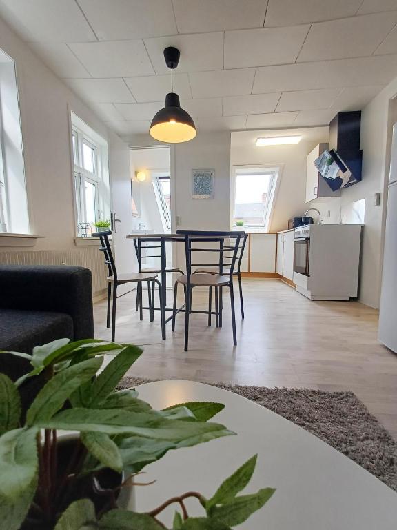 a living room with a table and chairs and a kitchen at Charming 1-bedroom Apartment A in Hjørring