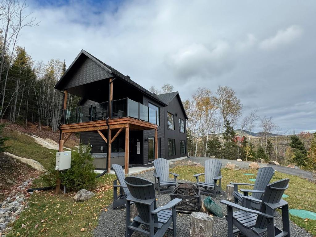a house with rocking chairs in front of it at Vertigo - Fleuve & Montagnes in Les Éboulements