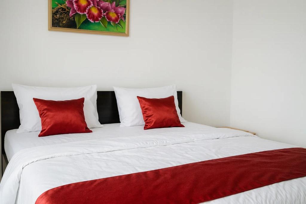 a bed with two red pillows on top of it at Cahaya Adrian Near Komodo Airport in Labuan Bajo