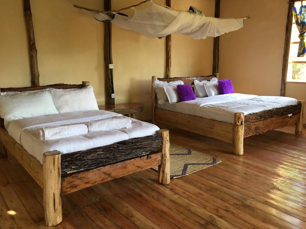 RubuguliにあるMigogo gorilla lodgeの木製の床の部屋にベッドが2つあります