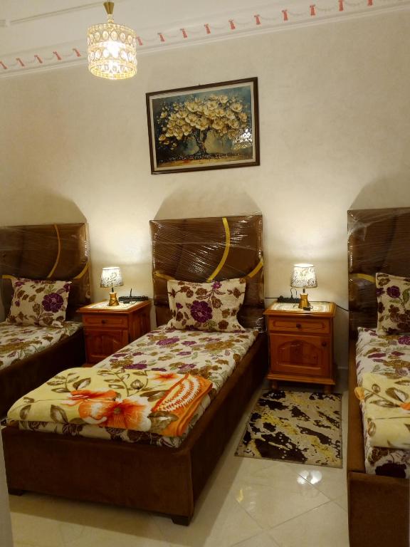 a bedroom with two beds and two night stands at Maison de vacances zuine in Oujda