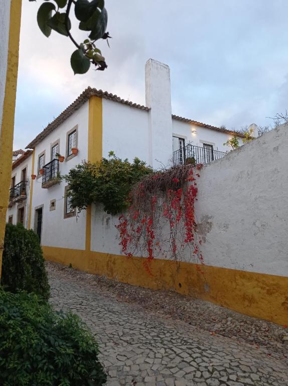 a white building with plants on the side of it at Casa das Glicínias in Óbidos