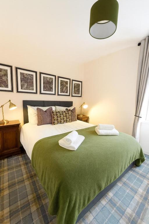 a bedroom with a green bed with two towels on it at Bed on the Brae in Inverness