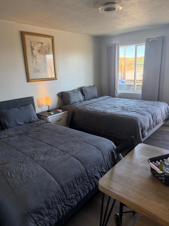 ein Schlafzimmer mit zwei Betten und einem Tisch und einem Fenster in der Unterkunft The Mint Motel in Rock Springs