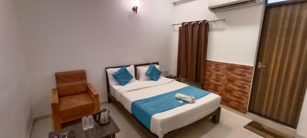 a bedroom with a bed and a chair in it at HOTEL MAHER Inn in Ahmedabad