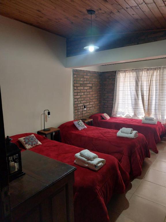 a room with three beds with red sheets at Emilia I in Esquel