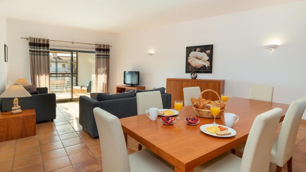 a dining room and living room with a wooden table at Marina Park 1721 in Albardeira