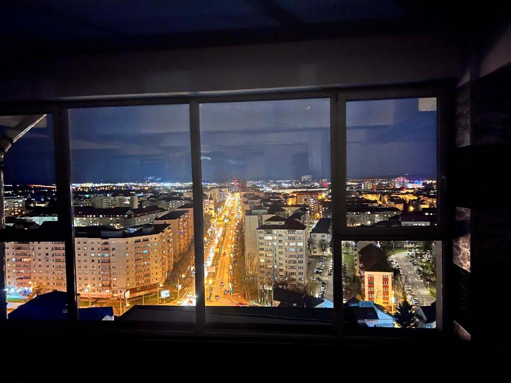 a view of a city at night from a window at Sky17 Penthouse Sibiu in Şelimbăr