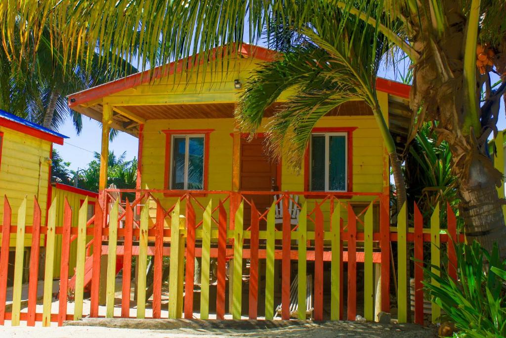 a yellow and orange house with a fence at Julia's Beachfront Guesthouse and Cabanas in Placencia Village