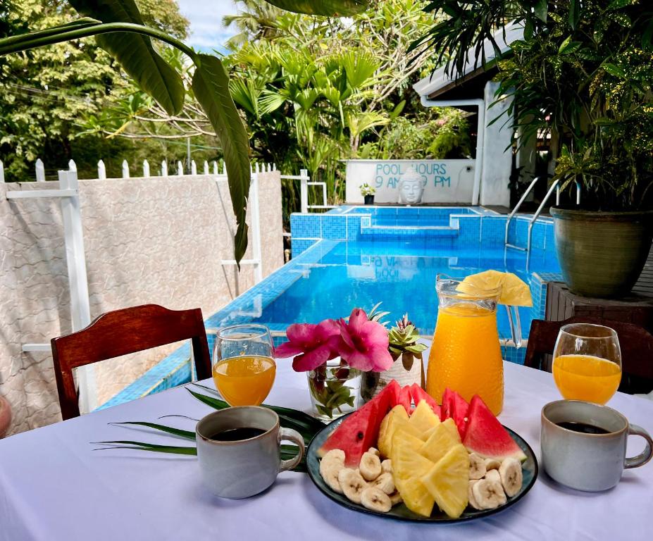 una mesa con un plato de fruta y zumo de naranja en Kika Zaru Free MA Park Tour & Breakfast, en Manuel Antonio