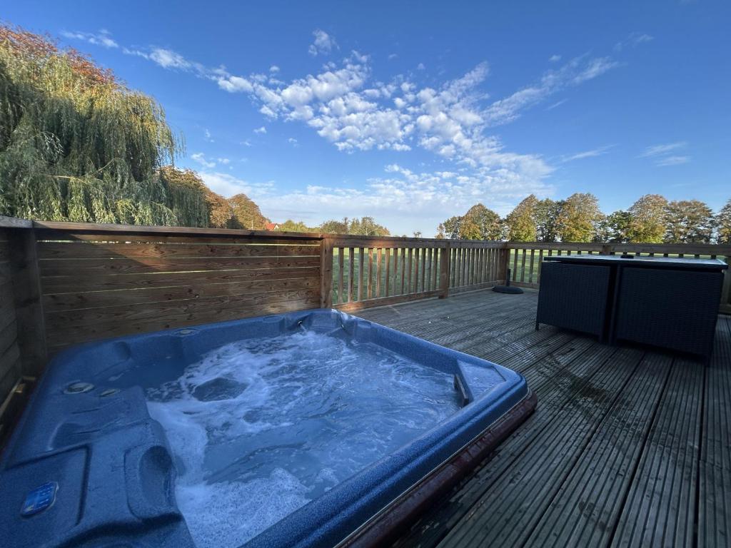 eine Whirlpool-Badewanne auf einer Holzterrasse in der Unterkunft Athelington Lodge - Oak in Horham
