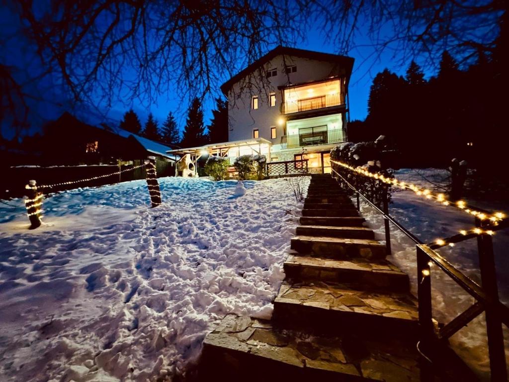 una casa con luces en la nieve por la noche en Iepurasul Sinaia, en Sinaia