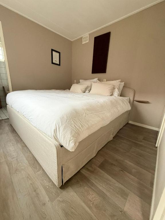Un dormitorio con una cama grande con sábanas y almohadas blancas. en Bed & Bloom, en Barneveld