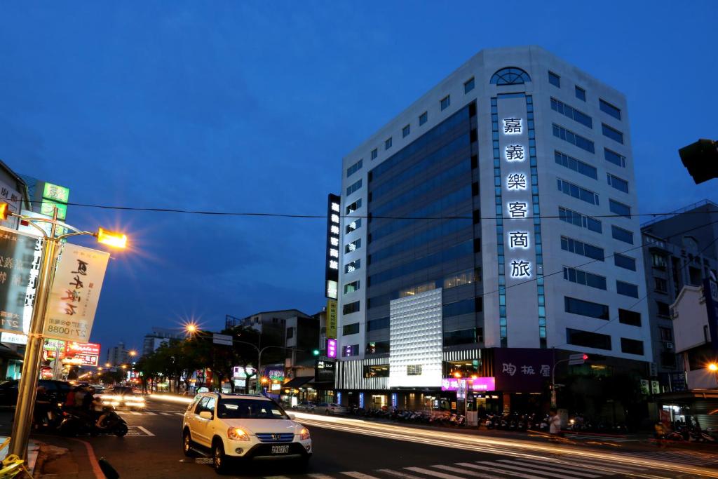 un coche blanco conduciendo por una calle de la ciudad por la noche en Chiayi Look Hotel, en Chiayi