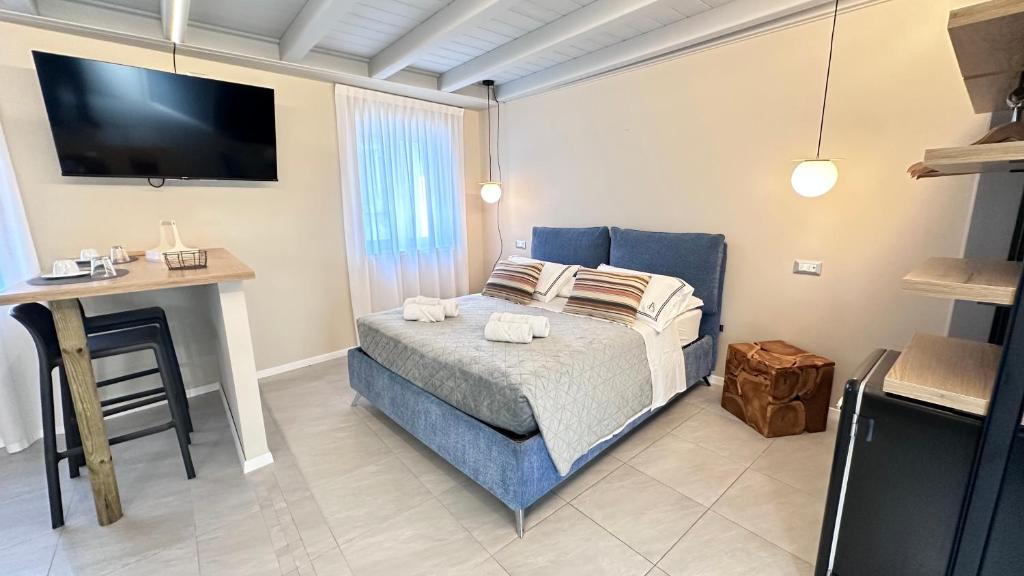 een slaapkamer met een bed, een bureau en een televisie bij ES Apartments in Nago-Torbole