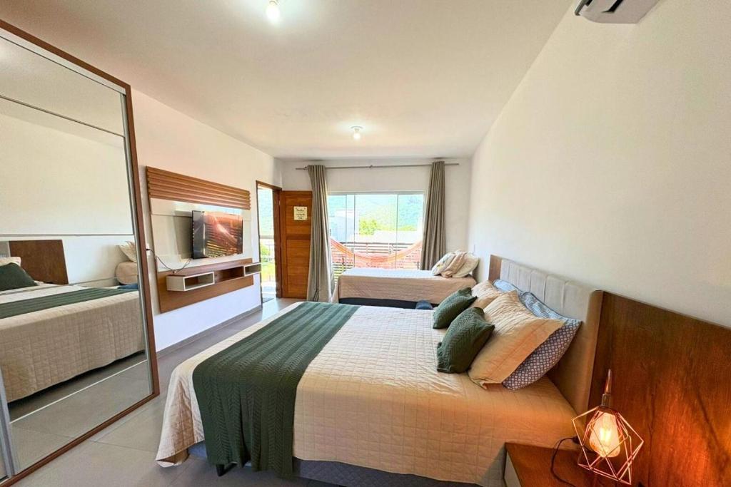 Un dormitorio con una cama grande y un espejo. en Dunas Studios, en Garopaba