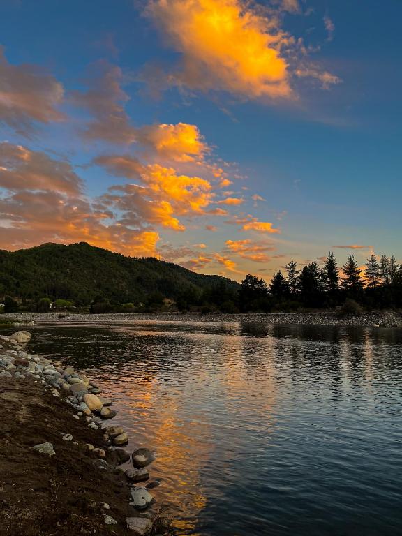 a sunset over a river with rocks in the water at NaboCamp in Linares