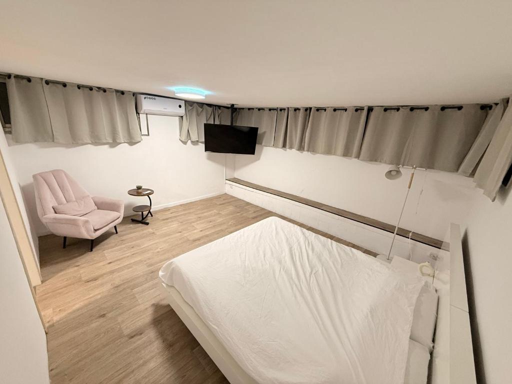 um quarto com uma cama, uma cadeira e uma televisão em SeaSide Villa em Asdode