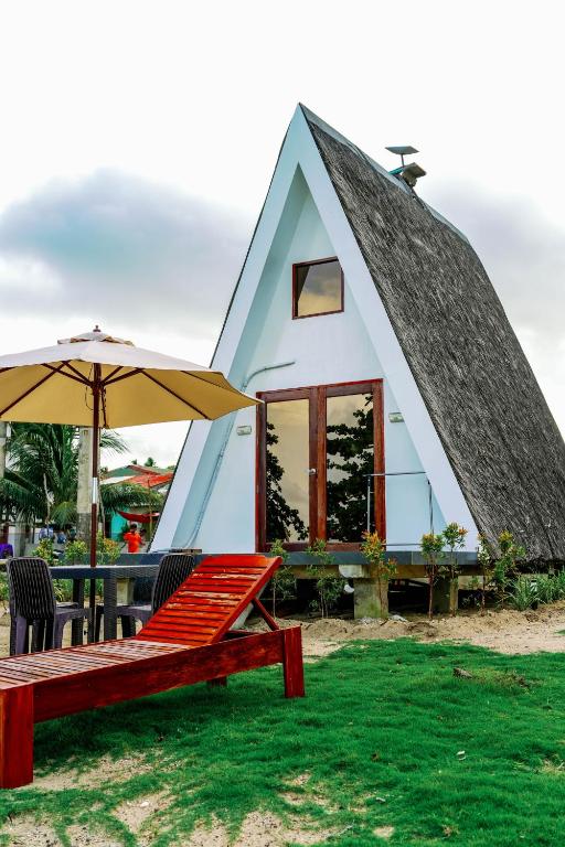 a house with a triangular roof with a bench and an umbrella at Filmegs Seaside in Alegria