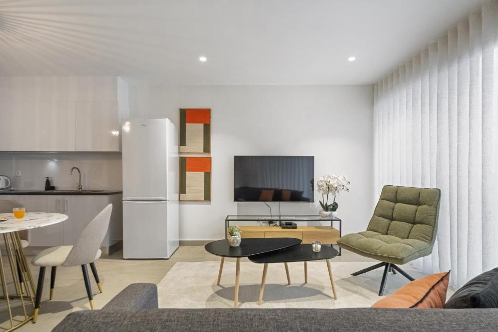 a kitchen and a living room with a table and chairs at Sunflower Gem by Homie in Caniço