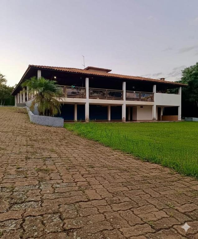 un edificio con un campo erboso di fronte di Sítio flor do campo a Sete Lagoas