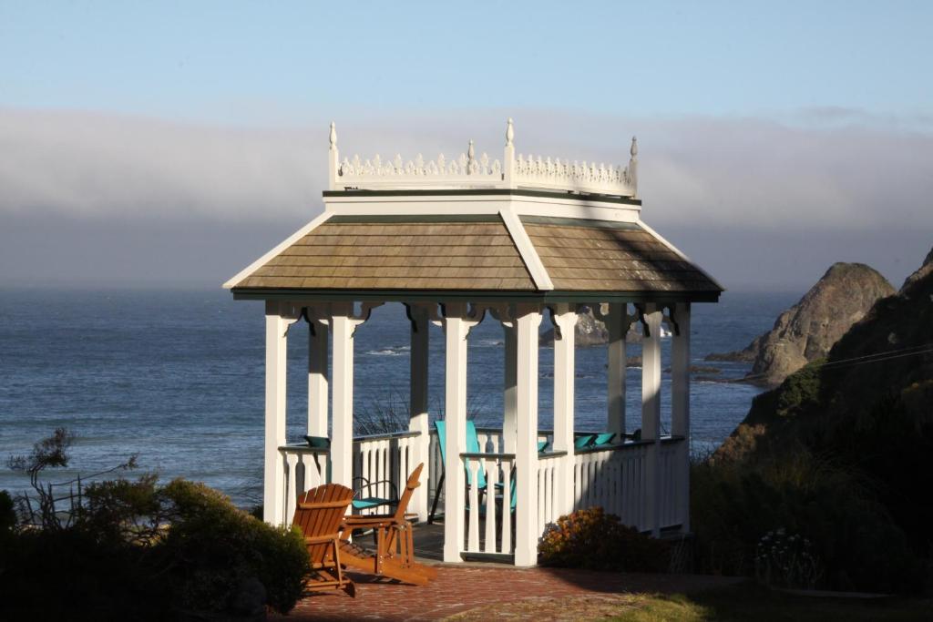 einen Pavillon mit zwei Stühlen vor dem Meer in der Unterkunft Elk Cove Inn & Spa in Elk