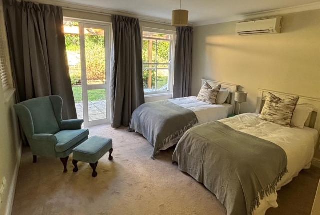 una camera da letto con due letti, una sedia e una finestra di Airlie Well a Constantia