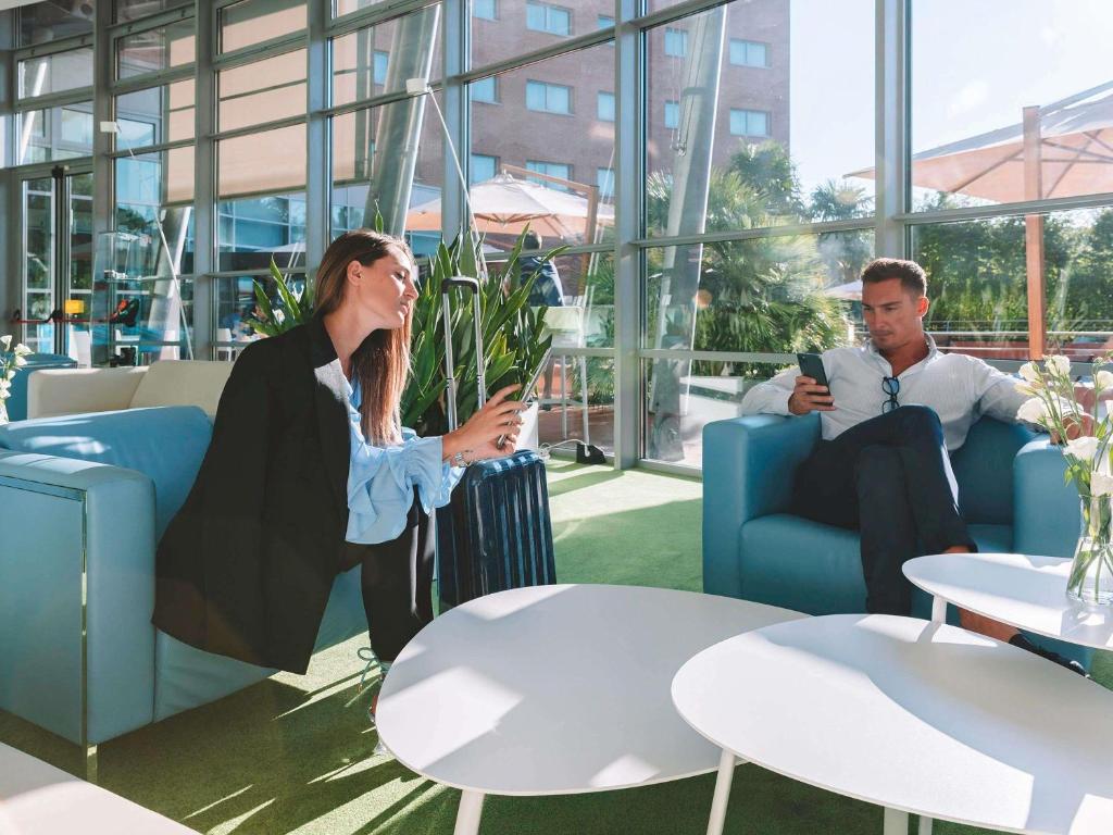 メストレにあるノボテル ベネチア メストレのオフィスの椅子に座っている男性と女性