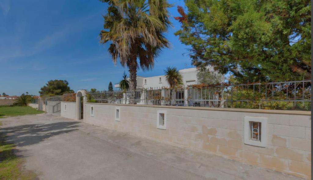 een bakstenen muur met een hek en een palmboom bij Elements Rooms in Porto Cesareo