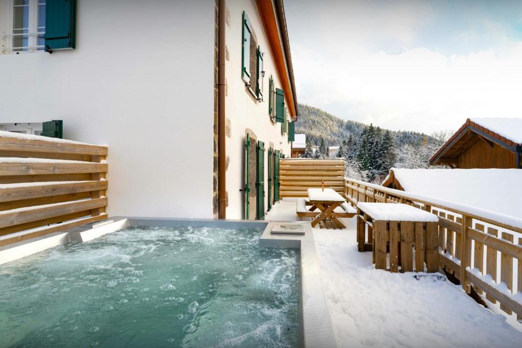 a hot tub on the side of a building in the snow at Le Refuge de Lucien - OVO Network in Gérardmer