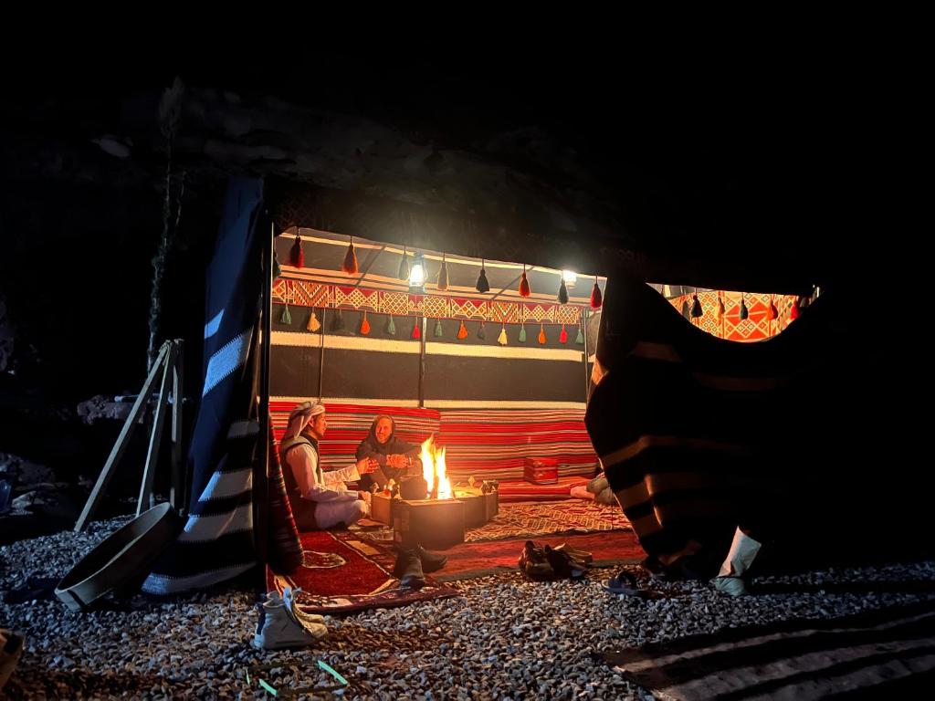 a group of people sitting around a fire in a tent at Wadi Rum Trip in Wadi Rum
