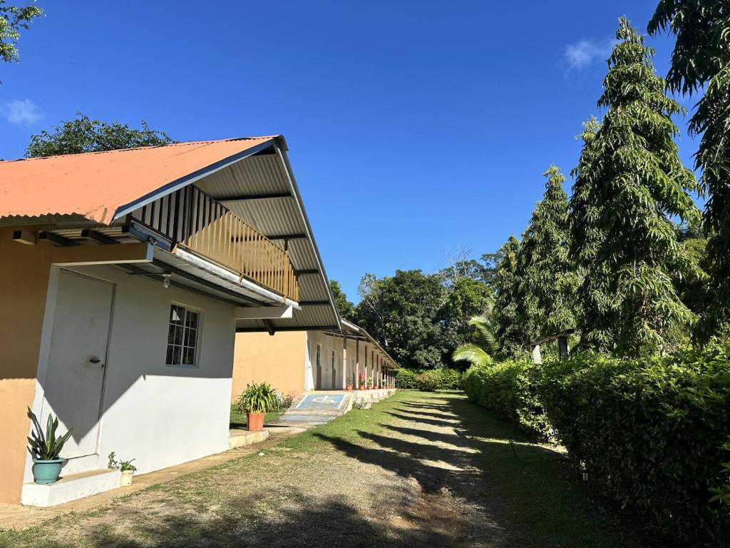 a white building with a red roof and some trees at Cabañas Green Hills in Las Minas