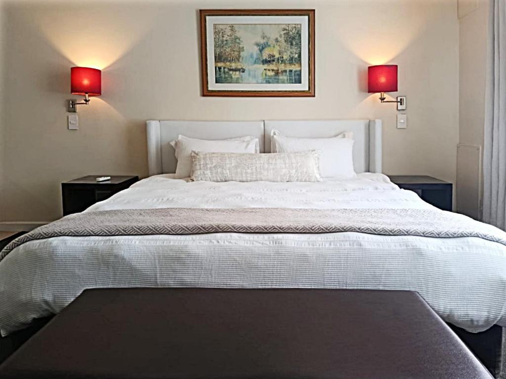 Cape Town CBD Pool Near CTICC Parliament Waterfront في كيب تاون: غرفة نوم بسرير أبيض كبير مع مصباحين أحمرين