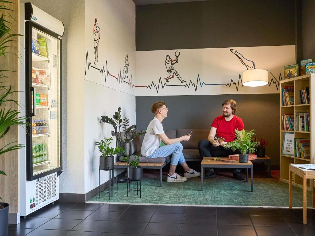 Dos personas sentadas en un sofá en una sala de espera. en ibis budget Wrocław Południe, en Wroclaw