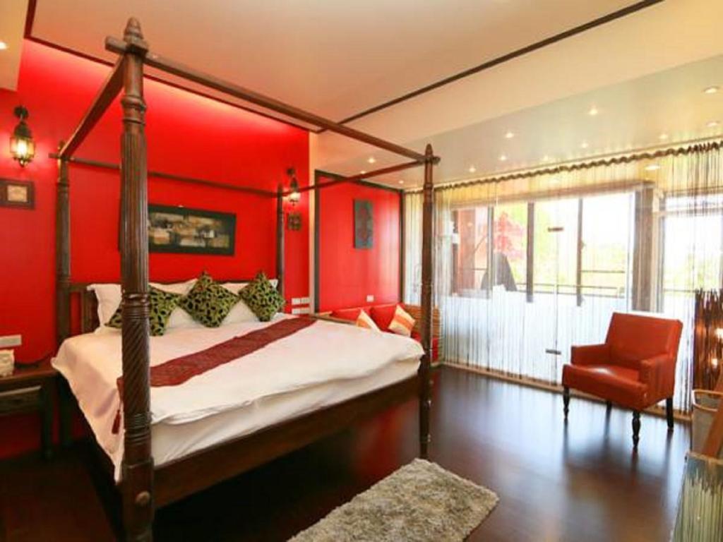 a bedroom with red walls and a bed and a chair at Mystery13 in Luodong