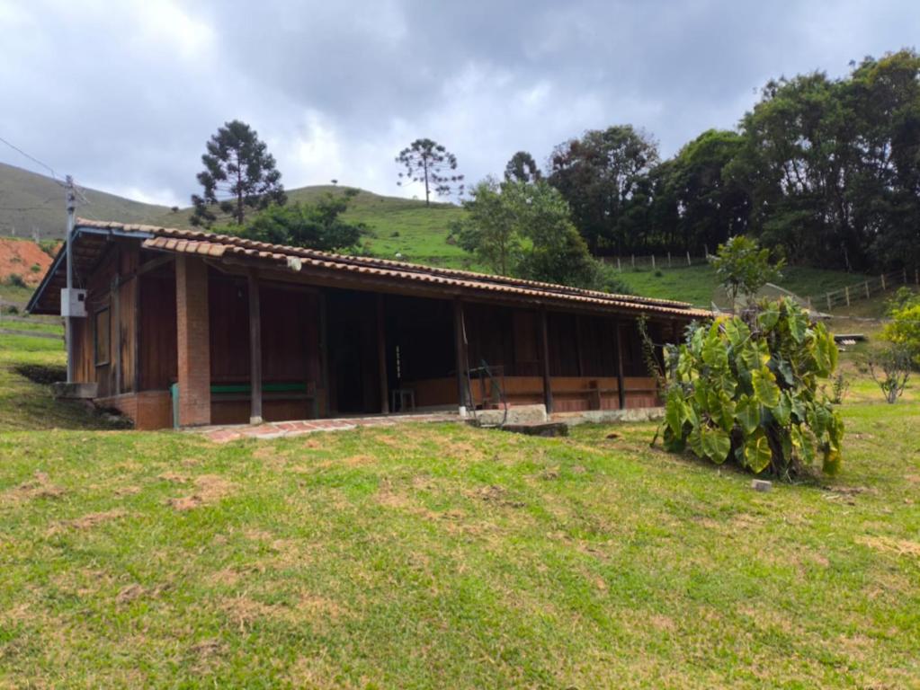 a house in a field with a tree at Sitio alto valinhos in Itamonte