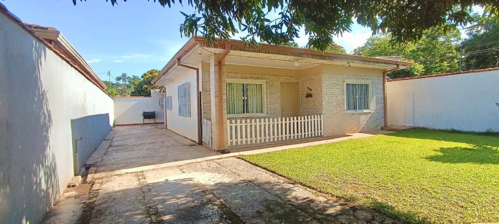 a small house with a white fence and a yard at Casa familiar completa con patio grande y estacionamiento en zona tranquila in Ciudad del Este