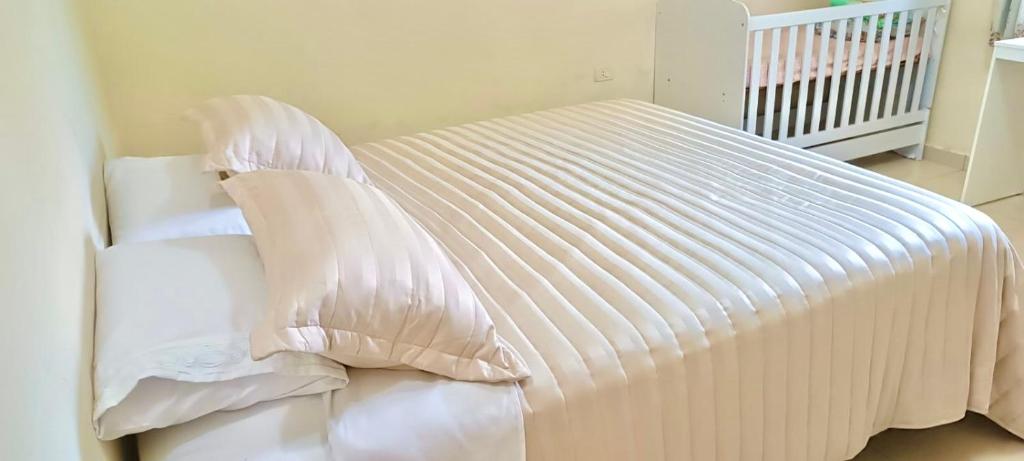 Una cama blanca con dos almohadas encima. en Casa familiar completa con patio grande y estacionamiento en zona tranquila, en Ciudad del Este