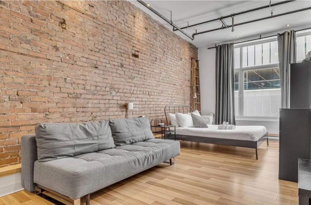 een woonkamer met een bank en een bakstenen muur bij District 202 Loft in Québec