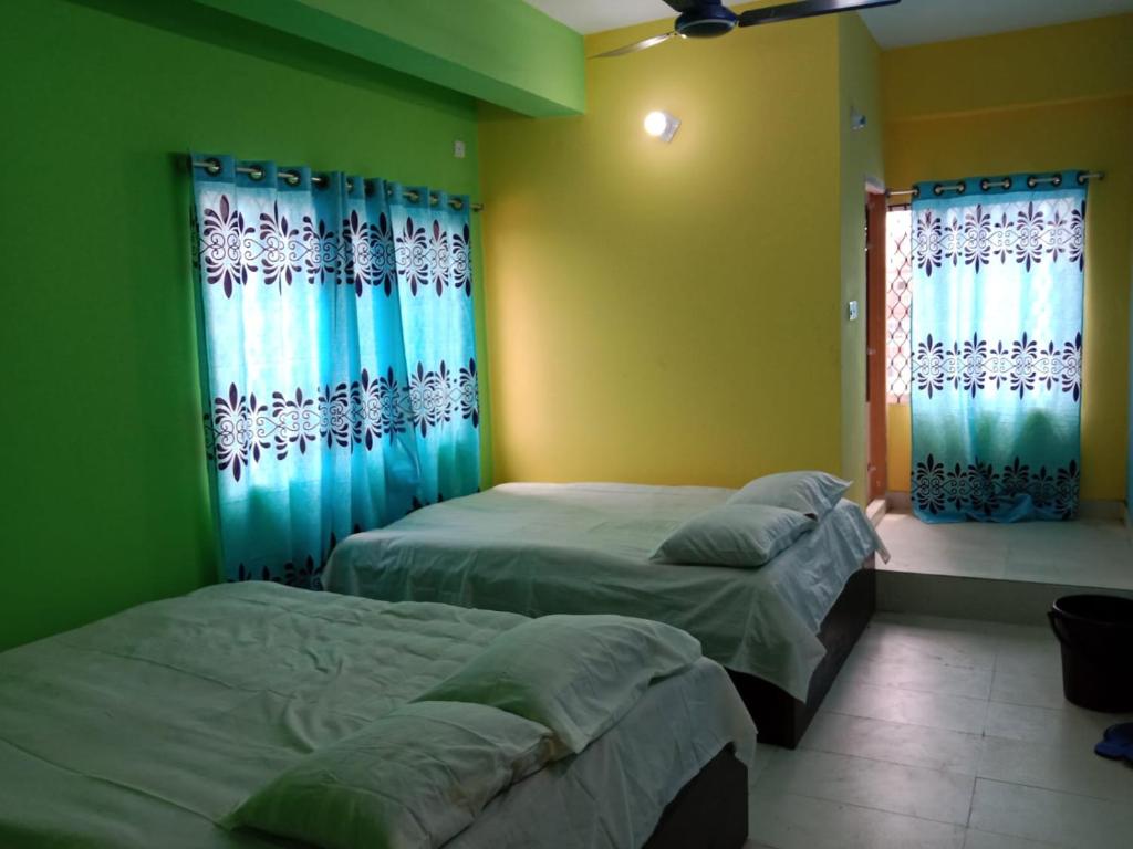 two beds in a room with green walls and windows at Hotel New View in Chittagong