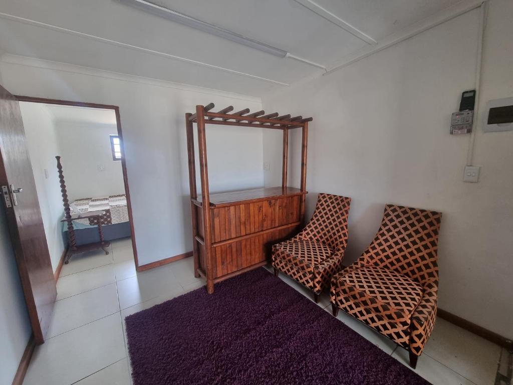 a living room with two chairs and a mirror at Bird Retreat in Zeekoevlei
