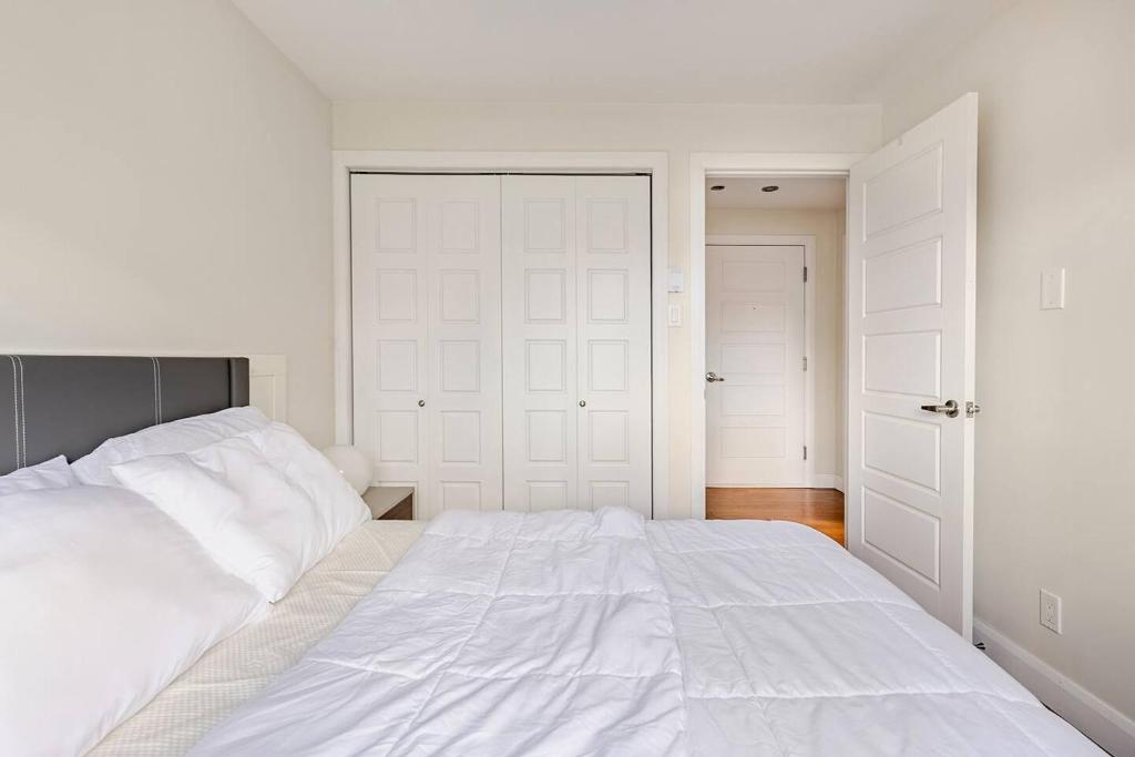 a bedroom with a large white bed and two closets at Voltaire 2 Appartement 4,5 , 2ch Laval, Canada meublé in Laval