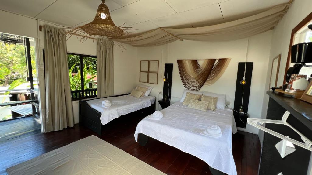 a bedroom with two beds and a large window at Chinuk Boutique Hotel in Puerto Viejo
