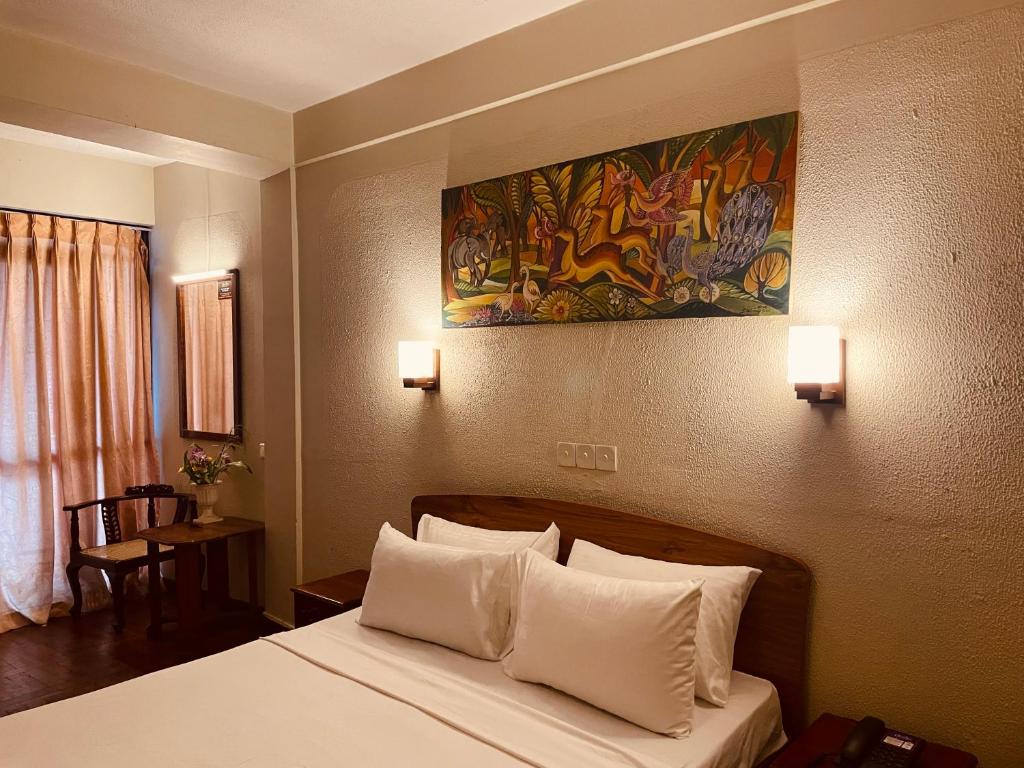 a hotel room with a bed with white pillows at Omega Regency Colombo in Colombo