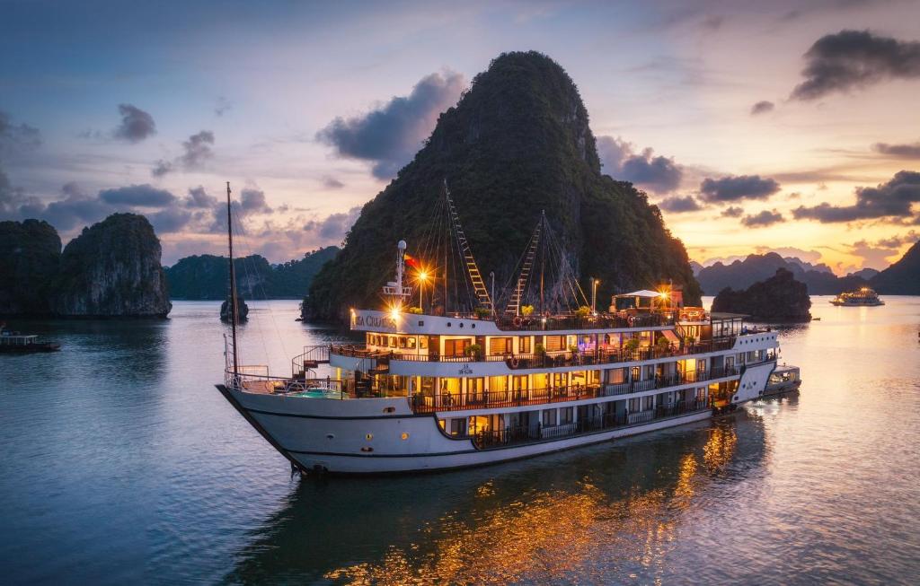 a boat in the water with a mountain in the background at Alisa Cruise Halong in Ha Long