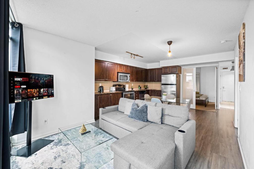 een woonkamer met een bank en een keuken bij Spacious 3BR Condo with Patio & Free Parking in Toronto