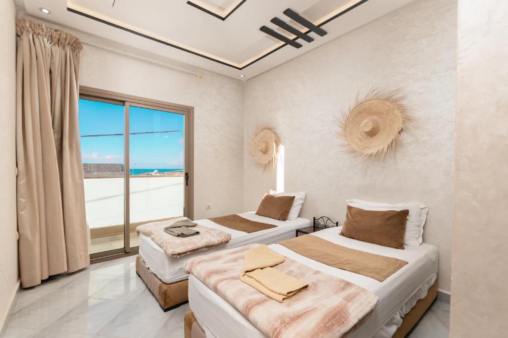 two beds in a room with a large window at jaws wave imsouane in Imsouane